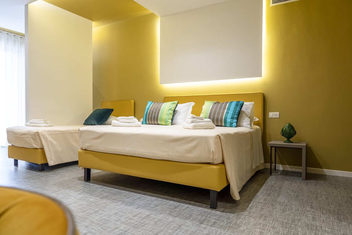 Camera dell'hotel con letti e parete gialla